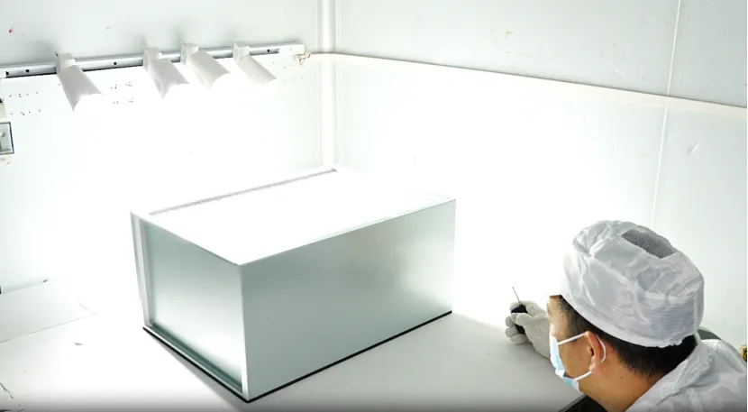 Technician inspecting a HEPA filter under bright lights.