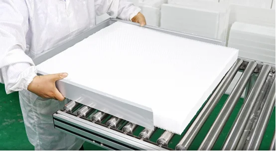 Worker assembling pleated mini-pleat HEPA filter on conveyor